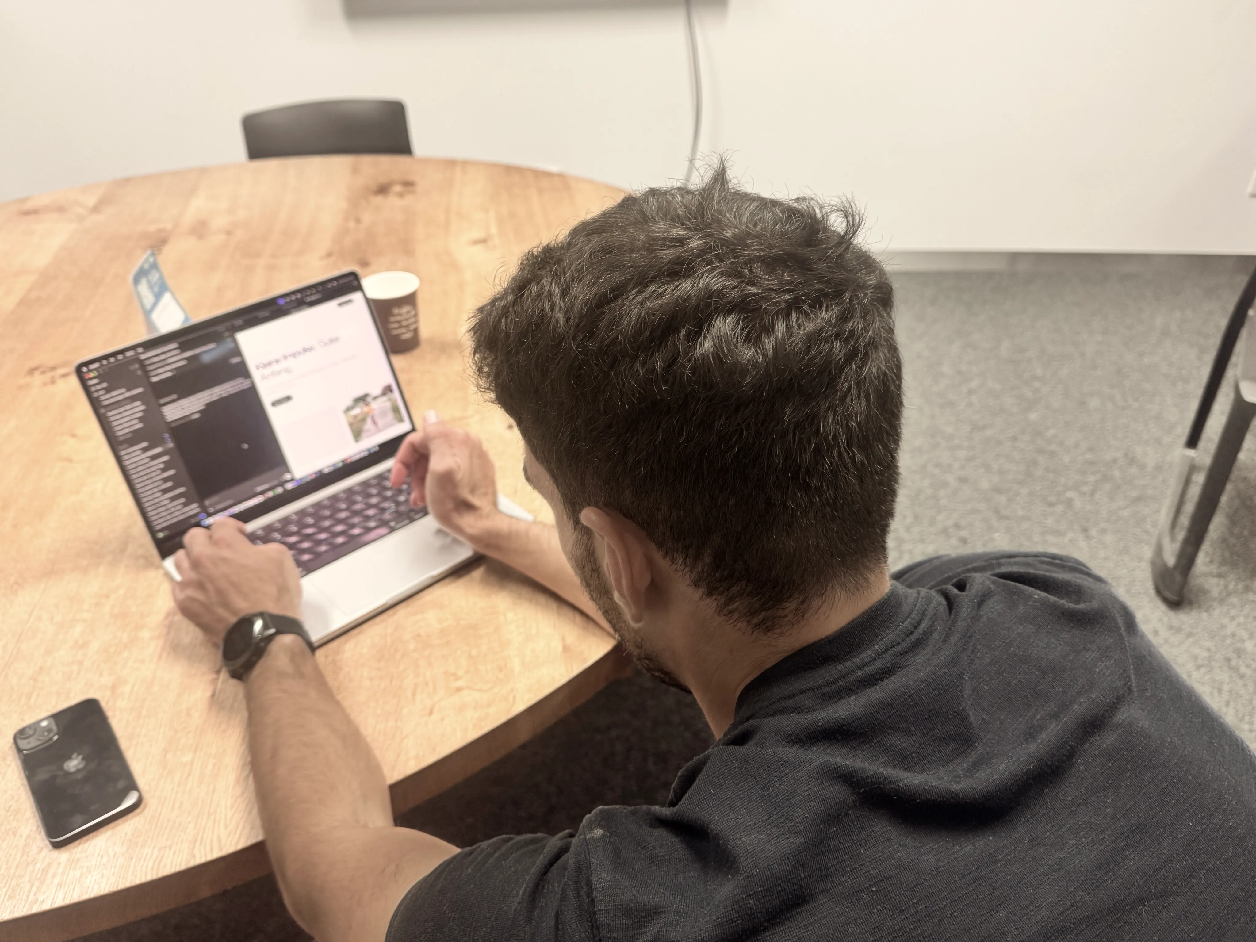 Felix at a table, seen from behind, building a website on his laptop with his coding agent